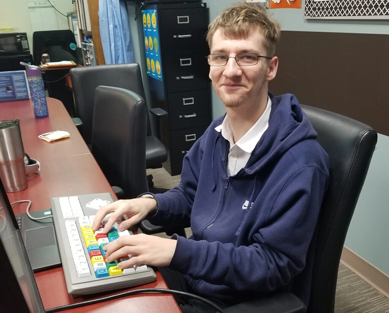 Noah sitting a computer station using the Big Keys Keyboard