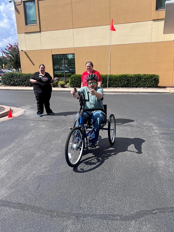 man with helmet riding in a handcycle in a parking lot